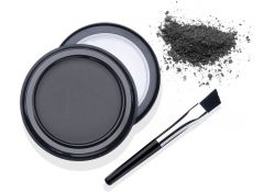 Open container of Ardell Brow Defining Powder Soft Black with cover and brush, powder on the background to feature its color